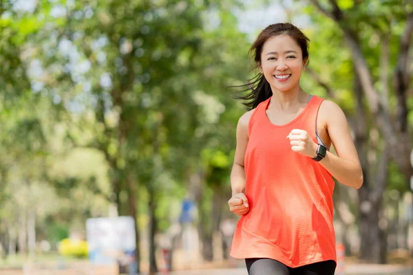 Healthy woman smiling and happy while jogging in the park in the morning.