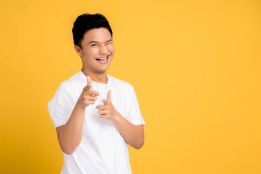 Beyaz tişört giyen genç Asyalı adam mutlu bir yüzü işaret ediyor. İzole edilmiş arkaplan.