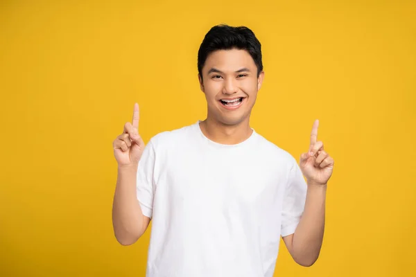 Jóképű Ázsiai Fiatalember Mosolyog Boldog Sárga Háttérrel Felemelte Kezét Felfelé — Stock Fotó