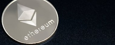 Siyah zemin üzerinde Ethereum gümüş sikkesinin (ETH) yakın plan fotoğrafı.