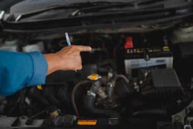 Genç oto tamircisi motoru kontrol ediyor. Motoru eliyle işaret etti..