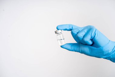 Yakın plan, beyaz arka planı olan çocuklar ve yetişkinler için bir şişe covid-19 aşısı taşıyor..