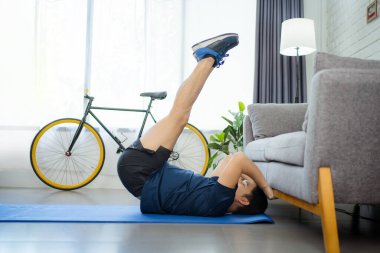 Sportif genç adam evde karın egzersizi yapıyor..