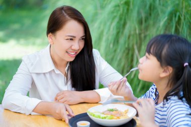 Gülümseyen anne çocuğu bahçede lezzetli bir kahvaltı yaparken mutluydu..