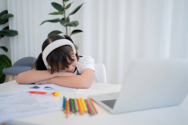 Asyalı kızlar evde internetten ders çalışıyor. Bilgisayarın önünde uyuyakalmış. Karantina ve koronavirüs salgınları sırasında evde eğitim. Sıkıcı ev eğitimi.