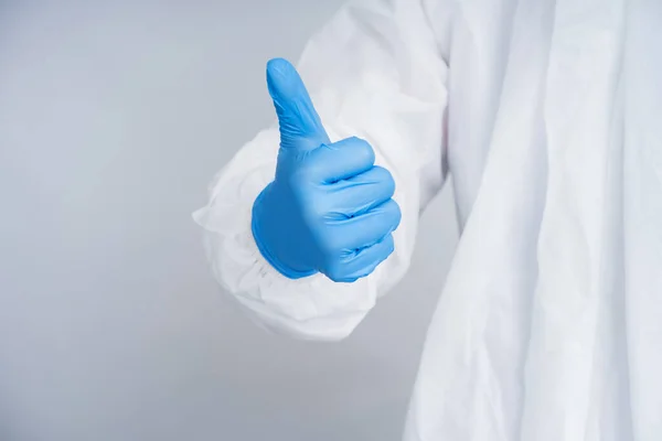 穿着防护服的医生戴上蓝色橡胶手套 他竖起大拇指 — 图库照片