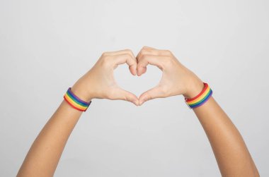 Genç bir kadının elleri, beyaz arka planda kalp şekli yaratıyor. LGBT, eşcinsel ilişkiler ve homoseksüel konsept.