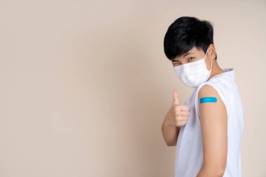 Kampanya aşısı, maske takan Asyalılar omzunu mavi bandajla gösteriyor, güvenli bir hayat, neşeli bir gülümseme..