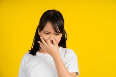 Küçük Asyalı kız pis ve dayanılmaz bir koku alıyor. Nefesini burnunda tutuyor..