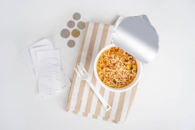 Beyaz bir masanın üzerinde bozuk para olan anlık erişte bardağı, ay sonu için yeterli para yok..