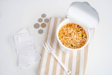 Masadaki hazır erişte bardaklarının, makbuzların ve bozuk paraların en üstteki fotoğrafı..