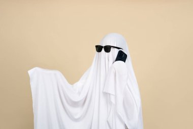 Ürkütücü hayalet. Bej arka planda beyaz çarşafla kaplanmış kişi