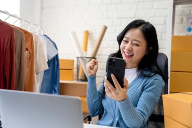 KOBİ Başlangıcı. Küçük işletme girişimcisi. Heyecanlı Asyalı Kadın Görme Başarısı Ellerini Kaldırıyor ve Smartphone 'da Online Pazarlama Kullanıyor. Paketleme ve nakliye. KME Konsepti.