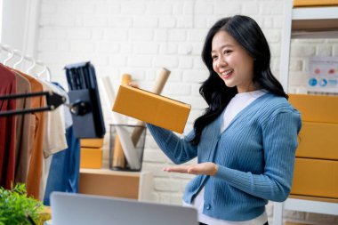 KOBİ Başlangıcı. Küçük işletme girişimcisi. Kameraya Karton Paket Gösteren Mutlu Asyalı Kadın. Çevrimiçi Piyasa Platformu üzerinden Giysi Satıcısı Kadın.