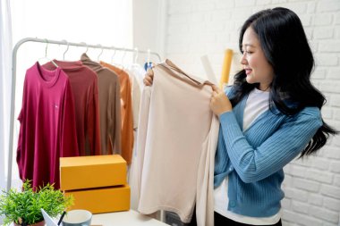 Mutlu bir Asyalı etken ya da KME dükkan sahibi evde çalışırken canlı, akıllı telefonu ve dizüstü bilgisayarında satmaktan keyif alıyor