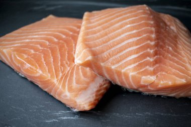 Siyah taş zemin üzerinde taze somon filetosu.