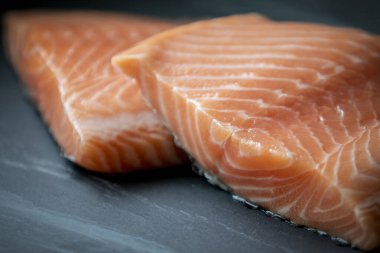 Siyah taş zemin üzerinde taze somon filetosu.