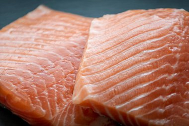 Siyah taş zemin üzerinde taze somon filetosu.