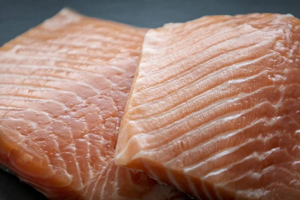 Siyah taş zemin üzerinde taze somon filetosu.