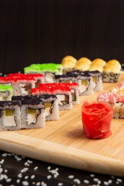 Siyah arka planda izole edilmiş hafif ahşap tabakta büyük suşi.