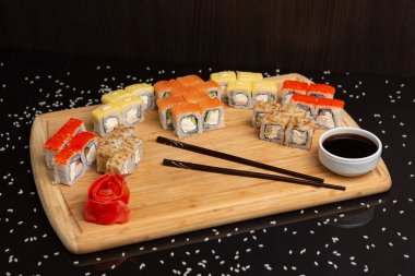 Siyah arka planda izole edilmiş hafif ahşap tabakta büyük suşi.