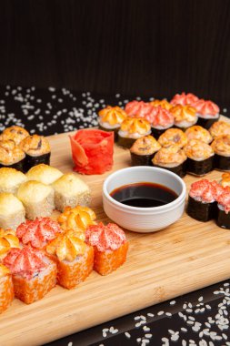 Siyah arka planda izole edilmiş hafif ahşap tabakta büyük suşi.