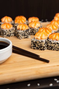 Siyah arka planda izole edilmiş hafif ahşap tabakta büyük suşi.