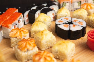 Siyah arka planda izole edilmiş hafif ahşap tabakta büyük suşi.