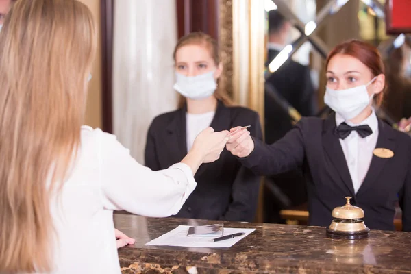 the hotel staff serves guests in medical masks