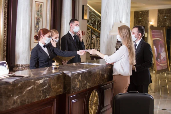 the hotel staff serves guests in medical masks