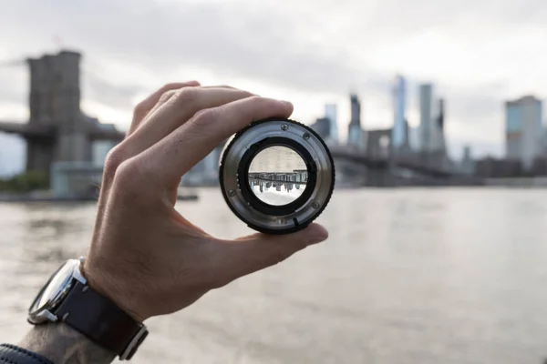 Mão segurando uma lente contra o horizonte de Nova York — Fotografia de Stock