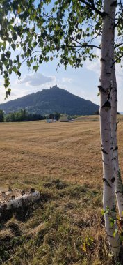 Hnvn Kalesi, Çek Cumhuriyeti 'nin Most şehrindeki bir tepenin tepesinde güneşli bir yaz gökyüzünün altında tünemişti. Tarihi şato şehre ve çevresindeki kırlara bakıyor, panoramik manzaralar sunuyor ve ortaçağ mimarisi sergiliyor.
