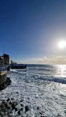 Madeira Adası 'ndaki küçük bir sahil kasabasında, adaların volkanik kökeninin göstergesi olarak kıyı şeridi boyunca siyah volkanik toprak bulunur. Kasaba iskelesi Atlantik 'e kadar uzanıyor, dalgaların kayalara ve kıyılara çarptığı ve dinamik bir hava yarattığı yere.
