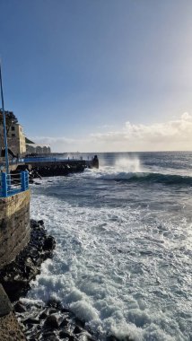 Madeira Adası 'ndaki küçük bir sahil kasabasında, adaların volkanik kökeninin göstergesi olarak kıyı şeridi boyunca siyah volkanik toprak bulunur. Kasaba iskelesi Atlantik 'e kadar uzanıyor, dalgaların kayalara ve kıyılara çarptığı ve dinamik bir hava yarattığı yere.