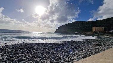 Madeira Adası 'ndaki küçük bir sahil kasabasında, adaların volkanik kökeninin göstergesi olarak kıyı şeridi boyunca siyah volkanik toprak bulunur. Kasaba iskelesi Atlantik 'e kadar uzanıyor, dalgaların kayalara ve kıyılara çarptığı ve dinamik bir hava yarattığı yere.