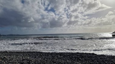 Madeira Adası 'ndaki küçük bir sahil kasabasında, adaların volkanik kökeninin göstergesi olarak kıyı şeridi boyunca siyah volkanik toprak bulunur. Kasaba iskelesi Atlantik 'e kadar uzanıyor, dalgaların kayalara ve kıyılara çarptığı yere, dinamik ve turbu yaratıyor.