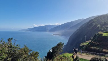 Madeira Adası 'nın kuzey kısmının kıyı manzarası, Atlantik Okyanusu' nun üzerinde yükselen yüksek uçurumlar. Güçlü dalgalar engebeli kıyı şeridine çarpar, dramatik bir hareket ve püskürtme yaratır. Sahne çiğ doğal enerjiyi vurgular, dik volkanik enerjiyi