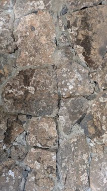 Yıpranmış dokusu ve doğal taş desenleri olan taştan bir duvarın yakın çekim görüntüsü..