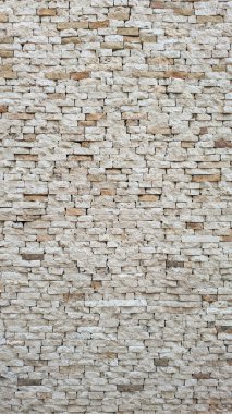 Renk ve hizada doğal varyasyonlara sahip desenli taş bir duvarın yakın plan görüntüsü.