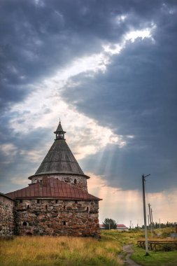 Solovetsky Manastırı 'nın Beyaz Kulesi mavi bulutların altında ve güneş ışınlı bir tavan penceresi altında.
