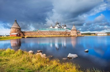 Solovetsky Manastırı, kutsal gölün kıyısından ve sudaki taşlardan Solovetsky Adaları 'ndaki sonbahar güneşinin ışınlarına.