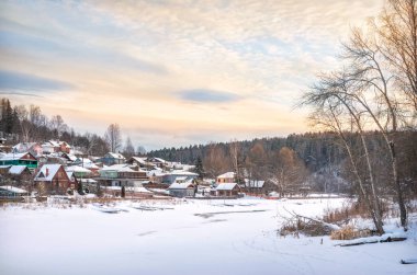 Karla kaplı Shokhonka nehrinin kıyısındaki ahşap evler Plyos 'ta kış sularının ışığında karlar altında.