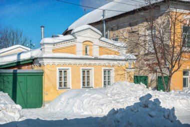 Murom 'da kışın güneşli geçen üç pencereli küçük sarı ev.
