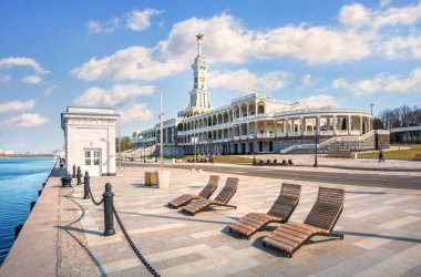 The building of the new River Station and sun loungers on the embankment of the Moskva River in Moscow on a spring sunny mornin clipart