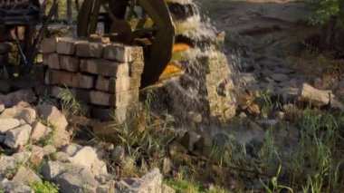An old water mill rotated by the flow of water. Splashes flying around. Slow motion.