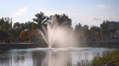 Resting place in the city park in the center of which there is a small pond with a fountain. Family weekend getaway.