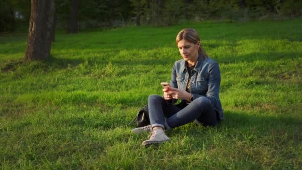 Una Giovane Donna Una Giornata Sole Siede Nel Parco Sull — Video Stock