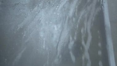 Sivrisinek ağını güçlü bir su basıncıyla temizliyorum. Ev temizliği. Yıkama sırasında su damlacıkları sıçratma.