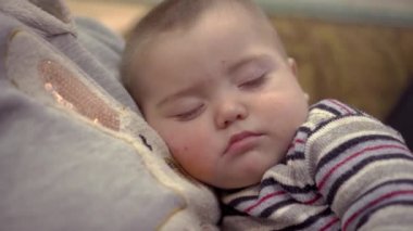 Bir yaşındaki küçük bir çocuk annesinin göğsünde uyuyor. Annelik ve çocuk bakımı kavramı. Sağlıklı bebek uykusu. Ailenin kollarında uyu..