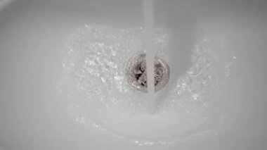 Su açık musluktan beyaz lavaboya akıyor.